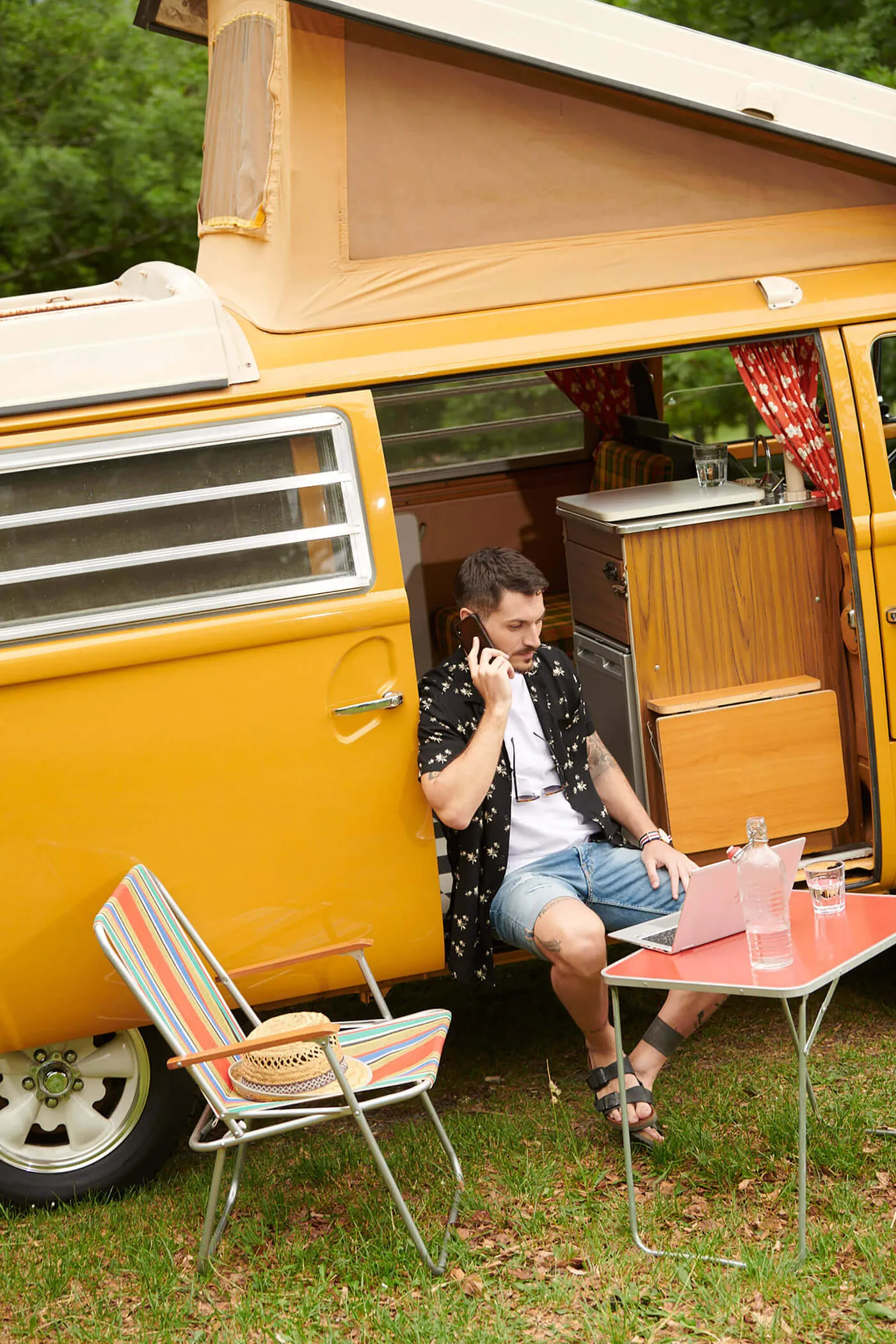 Junger Mann telefoniert vor einem Campingbus