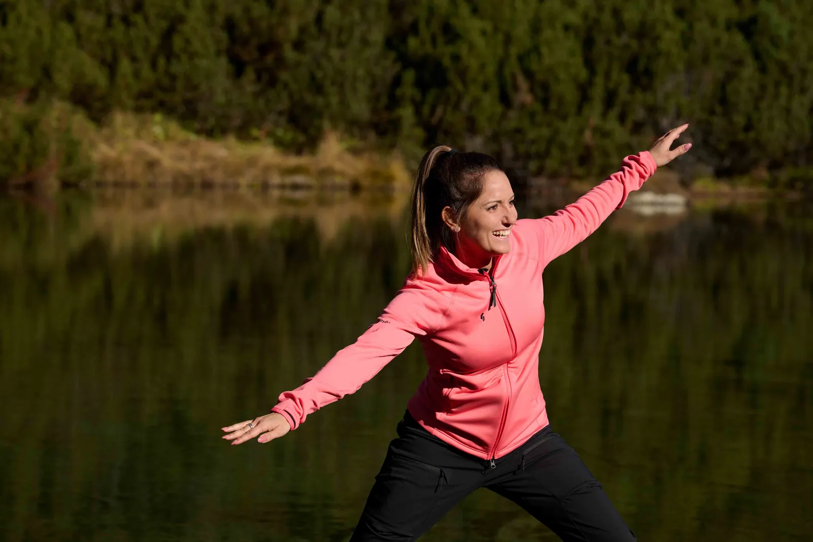 Junge Frau beim Balancieren vor dem tiefgrünen See.