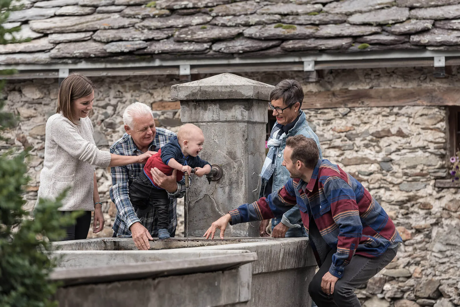 Familie spielt mit Baby am Brunnen