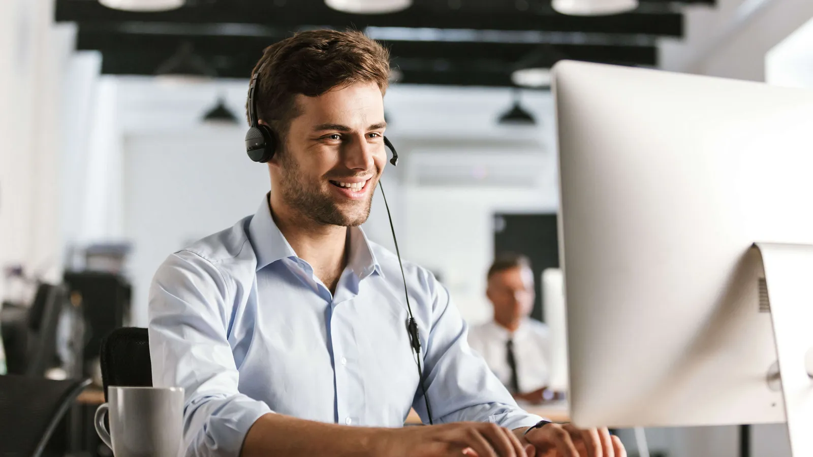 Mann mit Headset sitzt am Computer