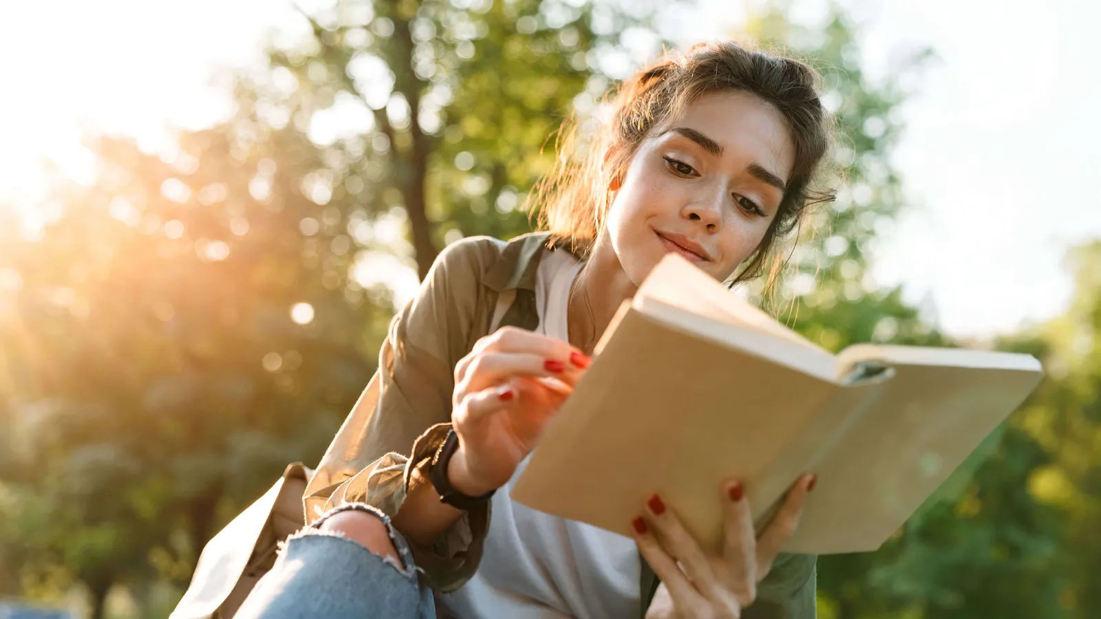 Eine junge Frau blättert draussen in einem Buch