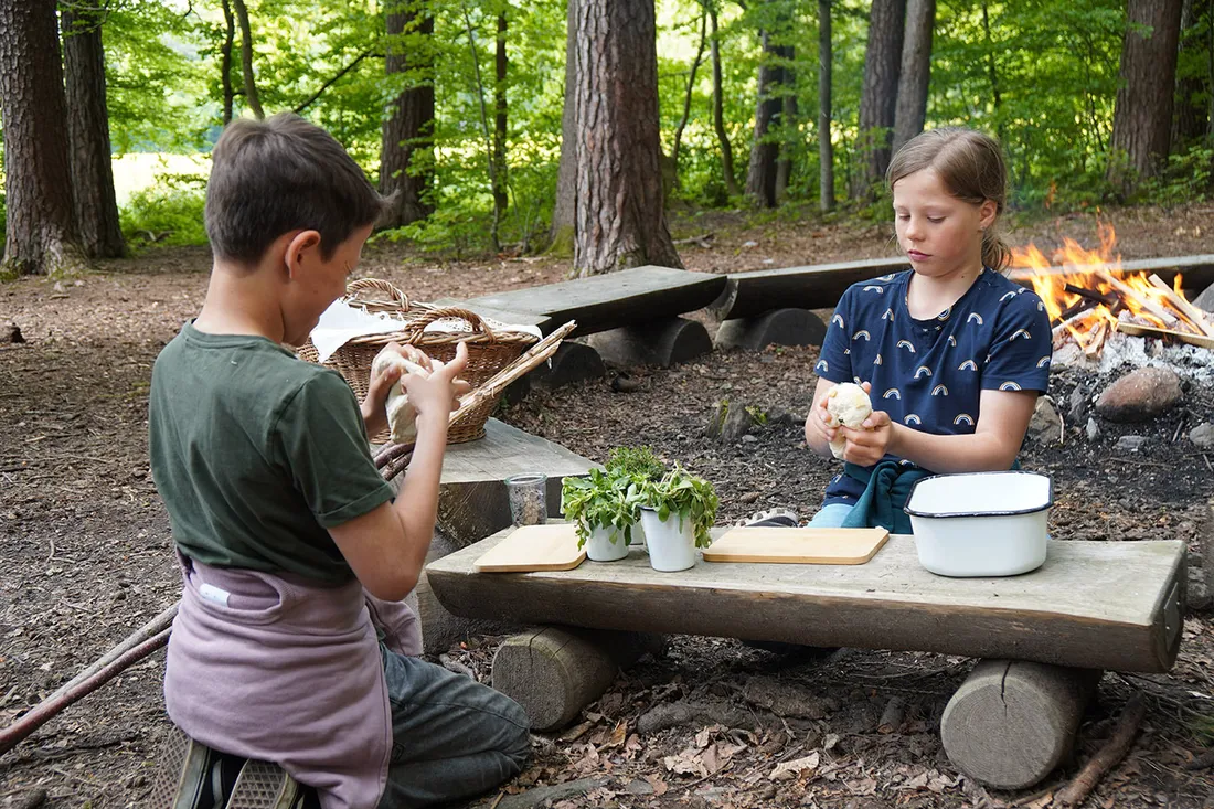 Zwei Kinder bei einer Feuerstelle im Wald