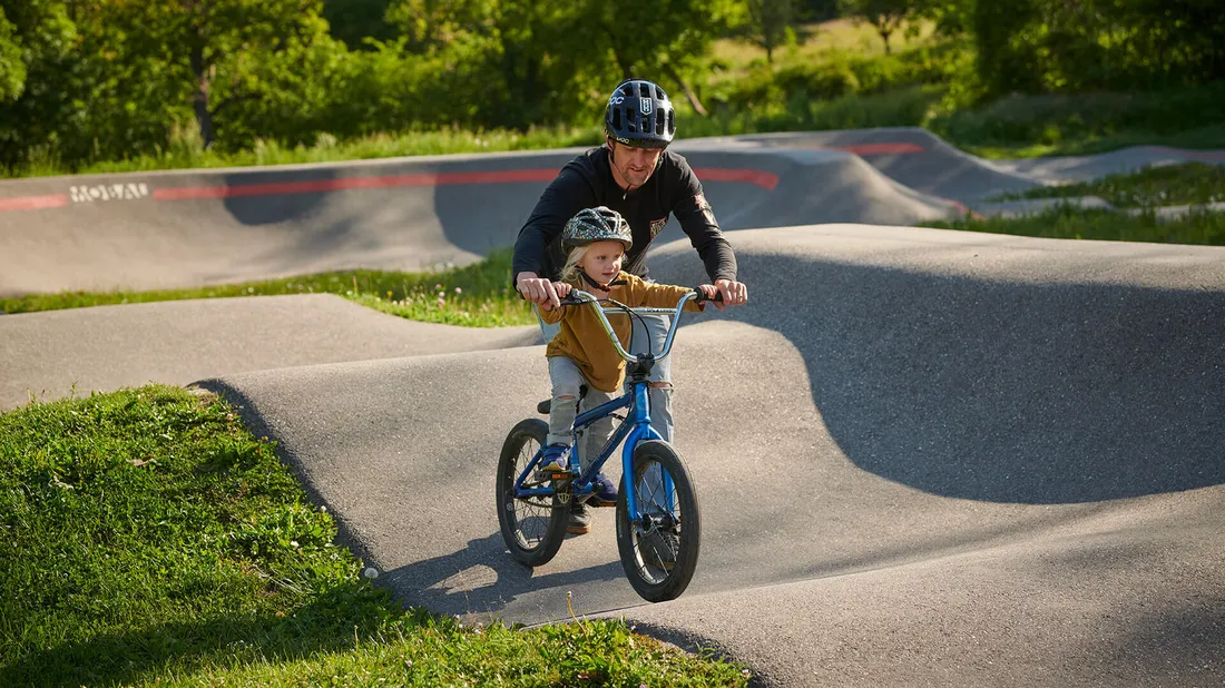 Vater mit Kind auf dem Pumptrack, die ein perfektes Kindervelo gekauft haben