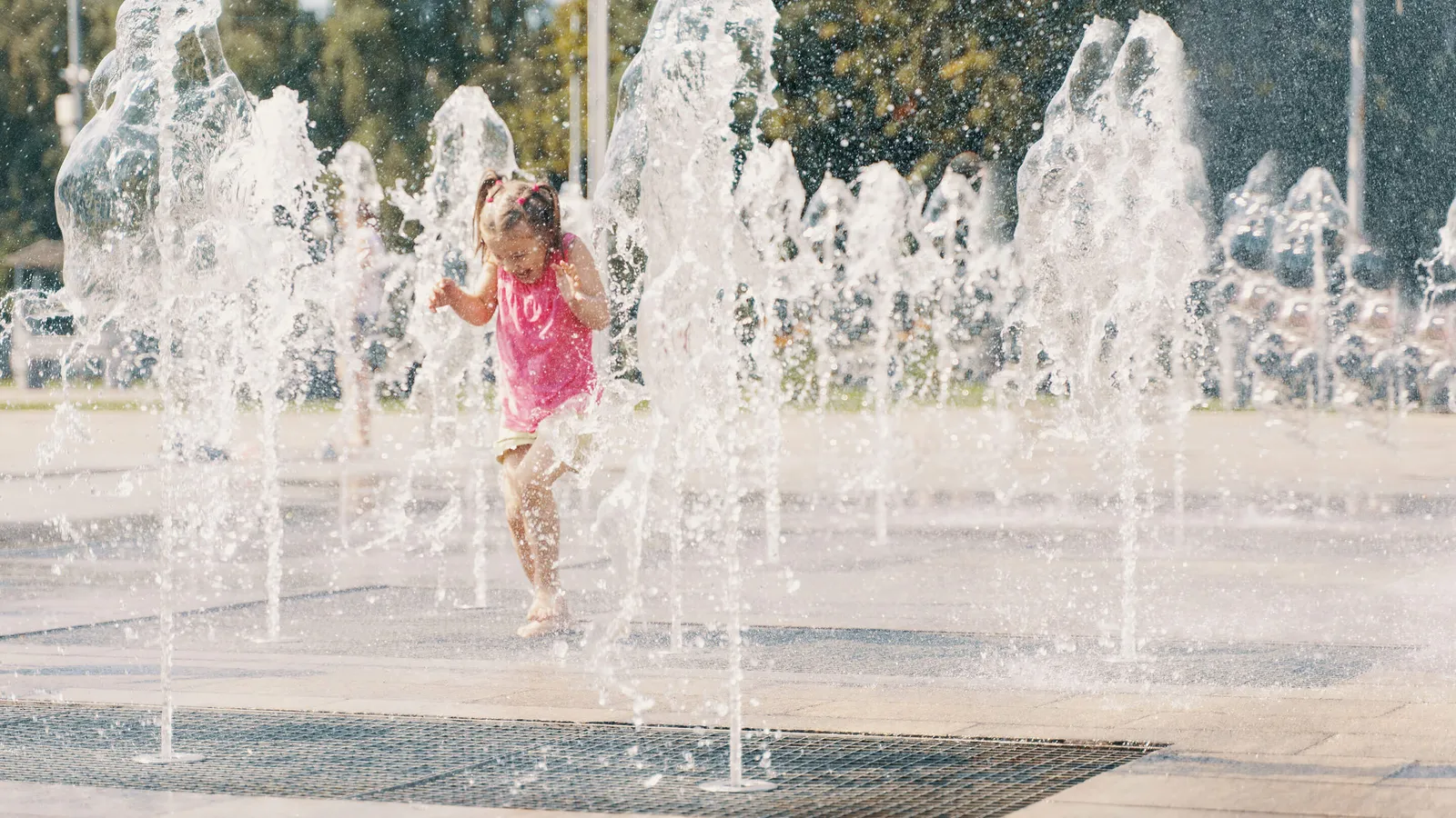 Mädchen springt durch einen Springbrunnen