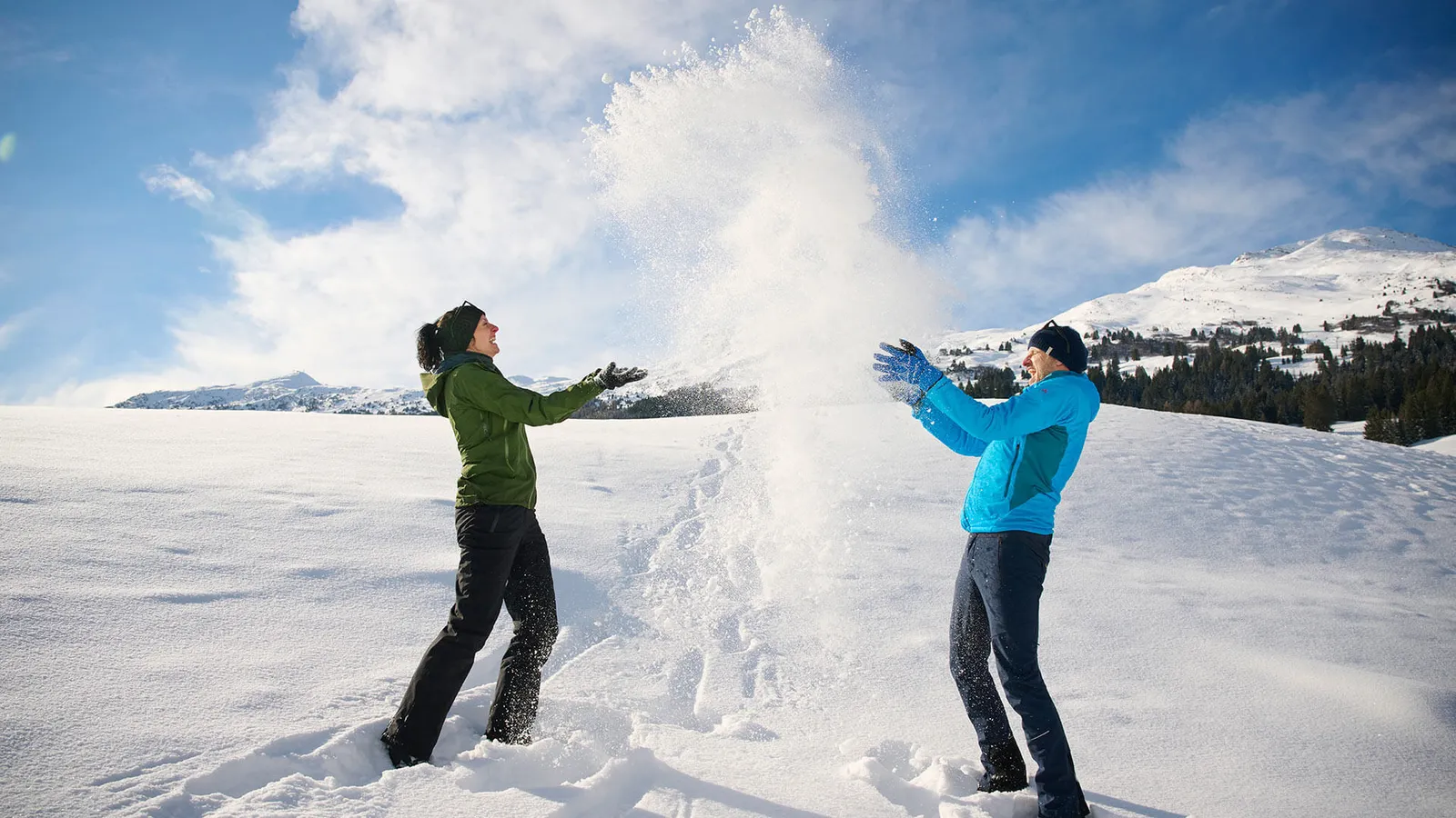 Mann und Frau werfen Schnee in die Luft