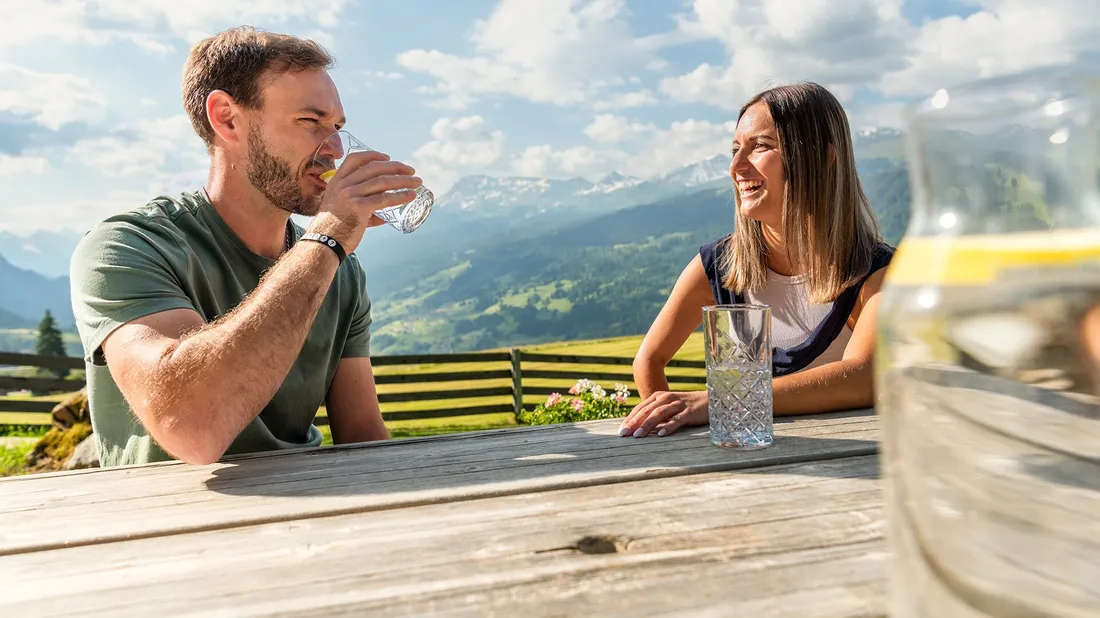 Mann und Frau sitzen an einem Picknicktisch und trinken Wasser