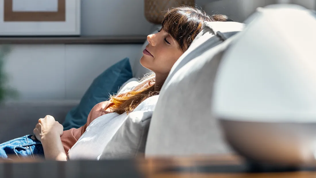 Eine Frau macht auf dem Sofa einen Powernap