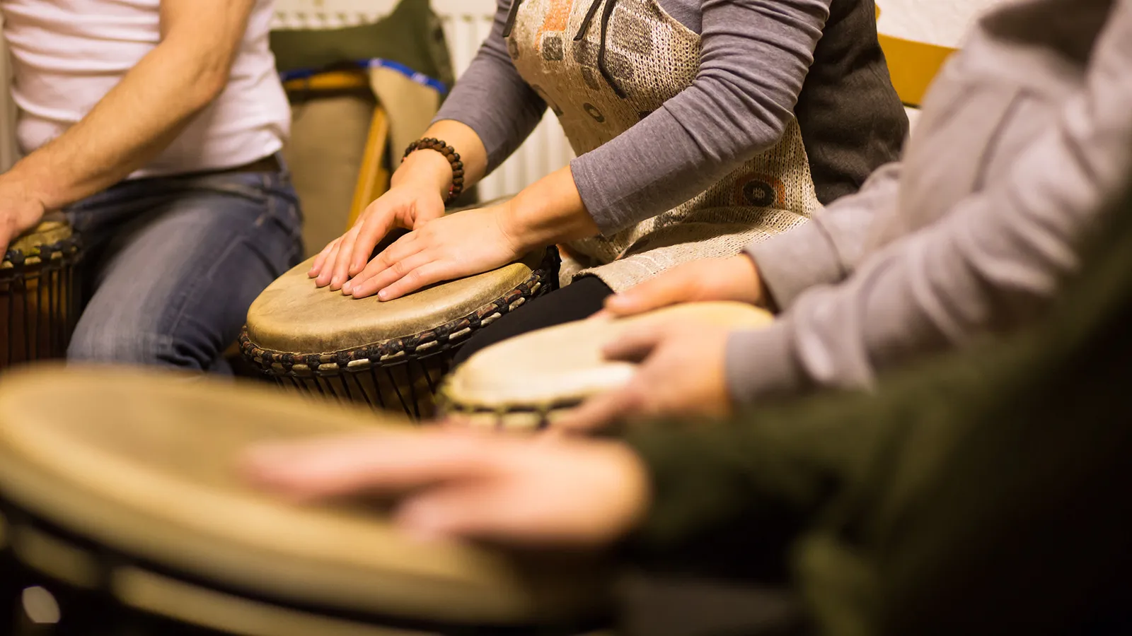 Mehrere Personen spielen im Rahmen einer Musiktherapie auf Trommeln