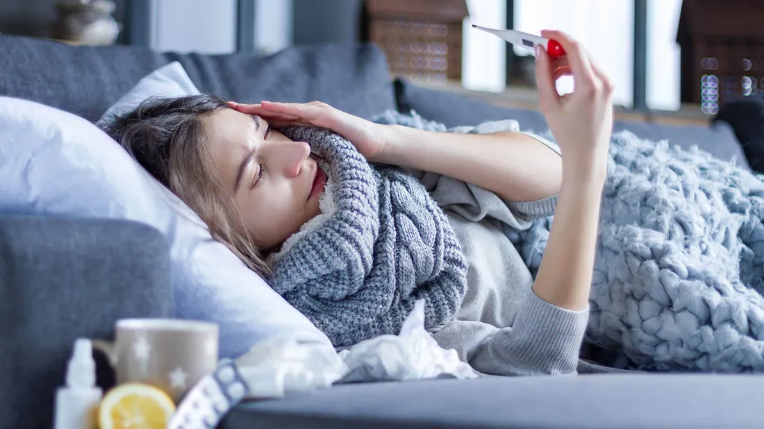 Frau liegt krank auf dem Sofa