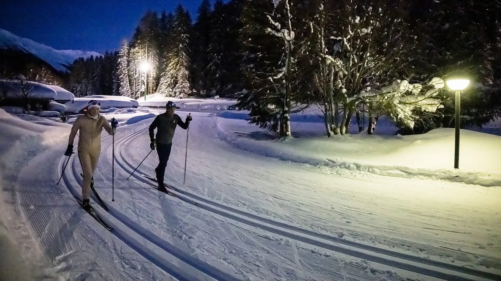 Zwei Personen auf der beleuchteten Nachtloipe in Davos