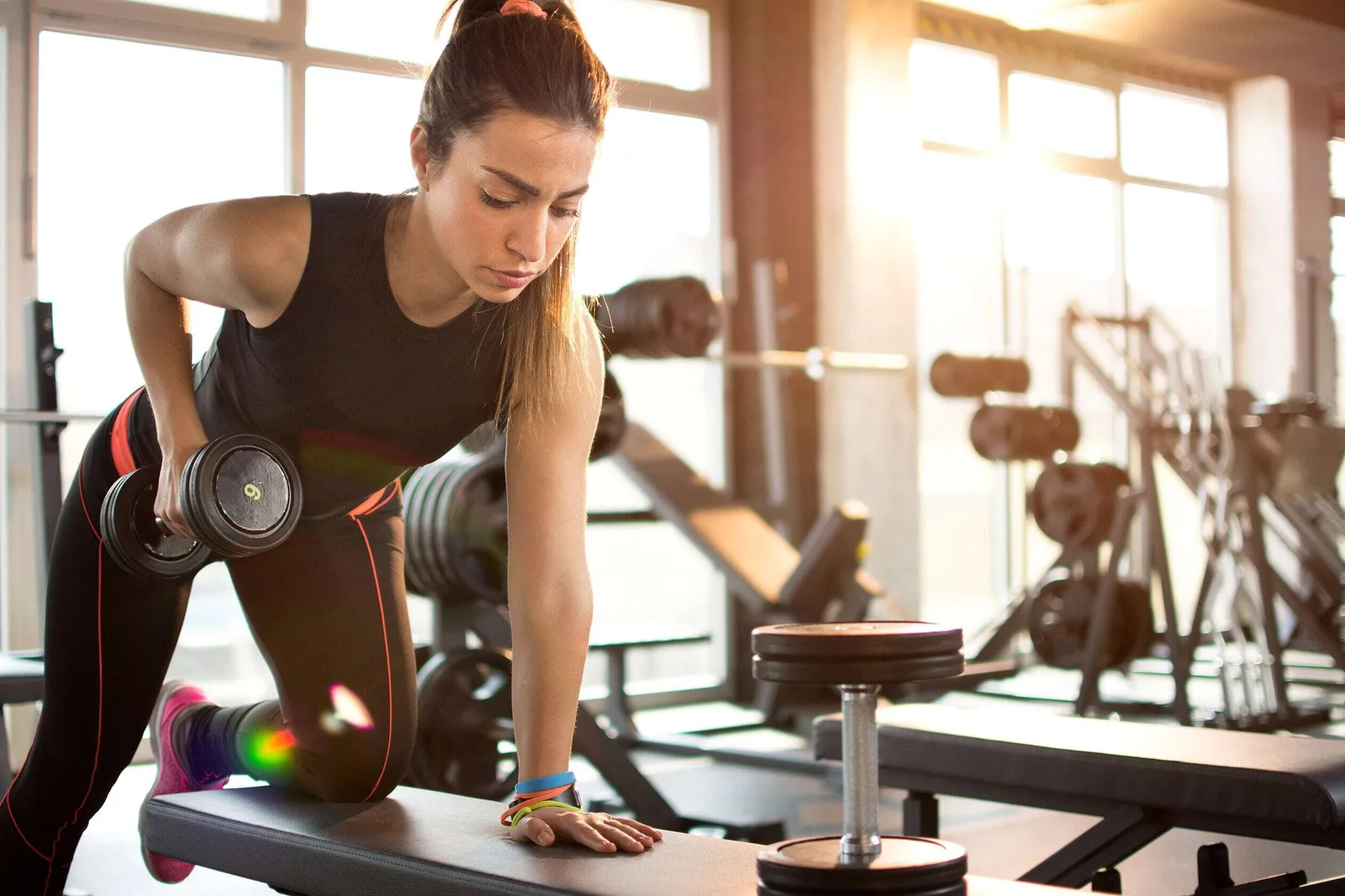 Junge Frau trainiert ihre Oberarme mit Hanteln im Fitnessstudio, um Muskeln aufzubauen.