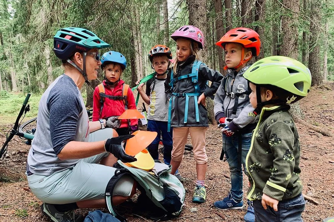 Frau erklärt Kindern etwas fürs Techniktraining auf dem Mountainbike