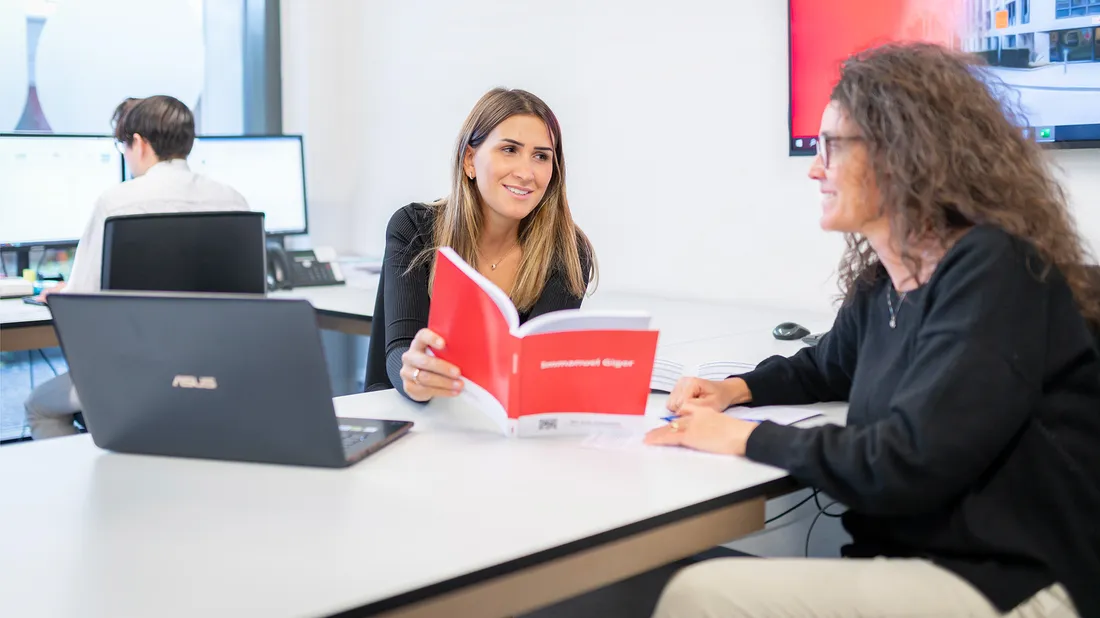 Zwei Frauen unterhalten sich im Büro über die Pensionskasse von ÖKK